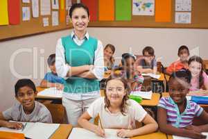 Teacher and pupils smiling at camera in classroom