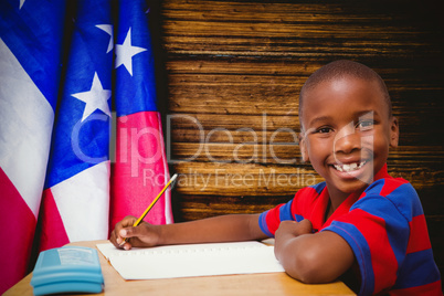 Composite image of happy pupil at desk