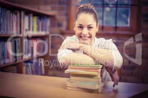 Blonde teacher leaning on pile of books in the library