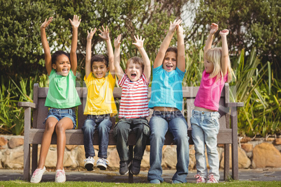 Smiling classmates sitting on bench and cheering