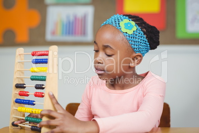 Focused pupil calculating with abacus in a classroom