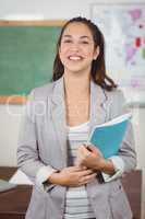 Pretty teacher holding notebook in a classroom