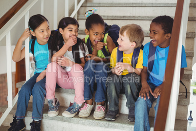 Happy pupils laughing and sitting on stairs