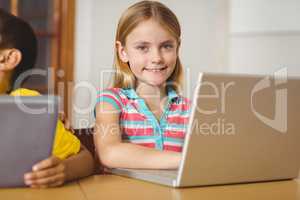 Cute pupil in class using laptop