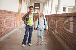 Smiling pupils holding hands at corridor