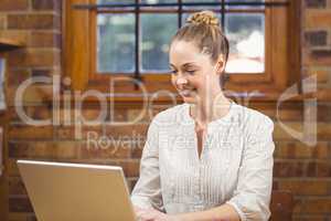 Blonde teacher using laptop in the library