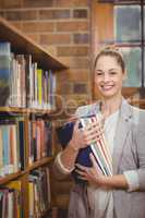 Blonde teacher holding books in the library