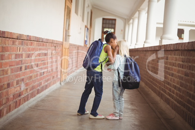 Cute pupils whispering secrets at corridor