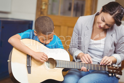 Pretty teacher giving guitar lessons to pupil