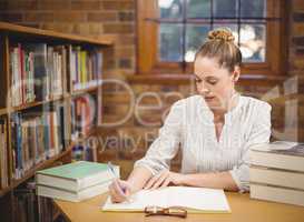 Blonde teacher correcting in the library