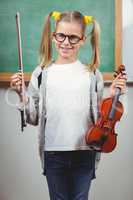 Cute pupil holding violin in a classroom