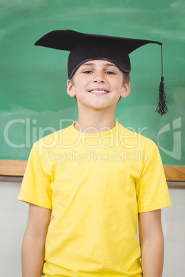 Smiling pupil with mortar board in a classroom