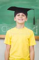 Smiling pupil with mortar board in a classroom