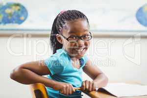 Cute pupil sitting at her desk in a classroom