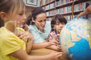 Pupils and teacher looking at globe in library