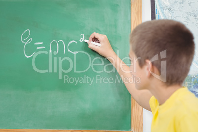 Cute pupil writing on chalkboard in a classroom