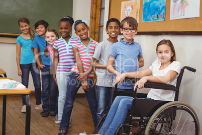 Disabled pupil smiling at camera with classmates