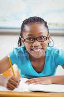 Smiling pupil working at her desk in a classroom
