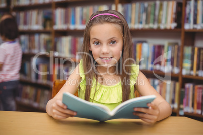 Pupil reading book at desk in library