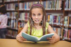 Pupil reading book at desk in library