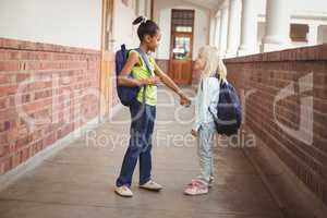 Smiling pupils holding hands at corridor