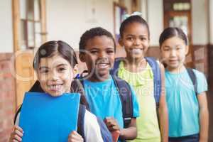 Cute pupils standing in a row at corridor