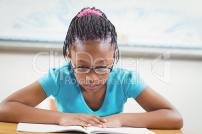 Focused pupil reading book in a classroom