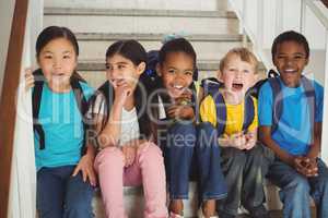 Happy pupils laughing and sitting on stairs