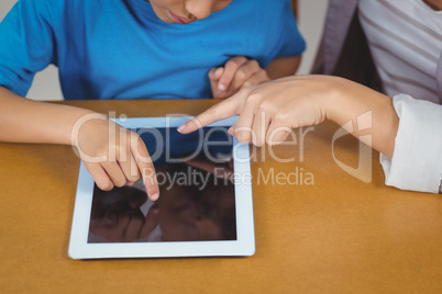 Teacher and pupil using tablet at his desk