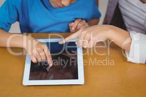 Teacher and pupil using tablet at his desk