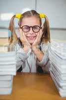 Smiling pupil between stack of books on her desk