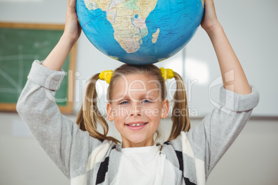 Cute pupil balancing globe on head in a classroom