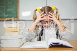 Concentrated pupil reading book at her desk