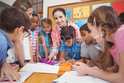 Teacher and pupils working at desk together