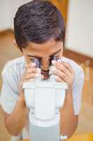 Pupil looking through microscope in class