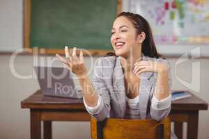 Pretty teacher sitting on chair and talking in a classroom
