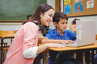 Happy teacher using laptop with student