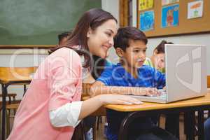 Happy teacher using laptop with student