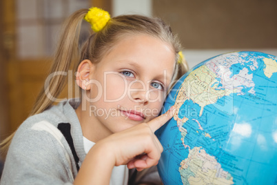 Cute pupil pointing on globe in a classroom