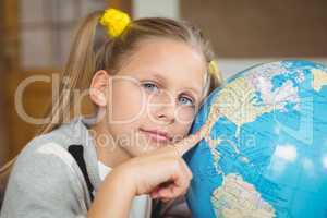 Cute pupil pointing on globe in a classroom