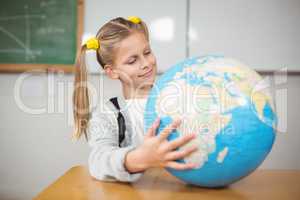 Cute pupil holding globe in a classroom