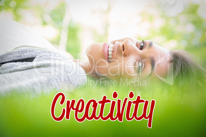 Creativity against pretty brunette lying on the grass