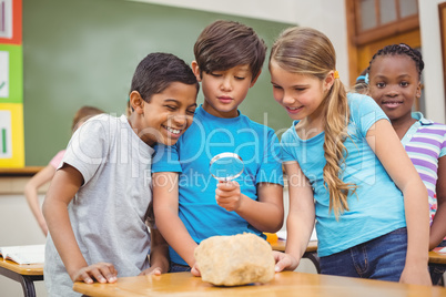 Pupils looking at rock with magnifying glass