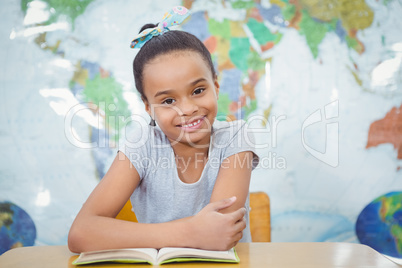 Smiling student with a book on the desk