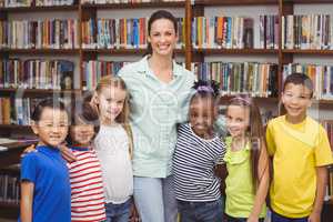 Pupils and teacher smiling at camera in library