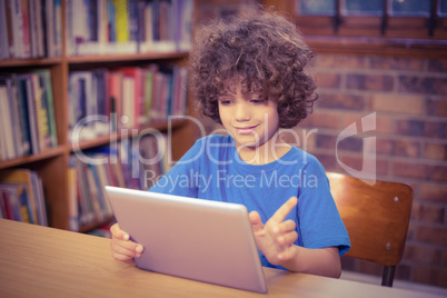 Cute pupil using tablet in the library