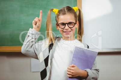 Cute pupil holding books in a classroom