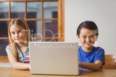 Cute pupils in class using laptop