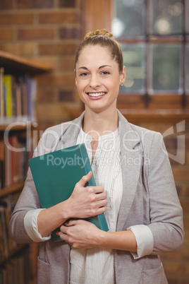 Blonde teacher holding book in the library