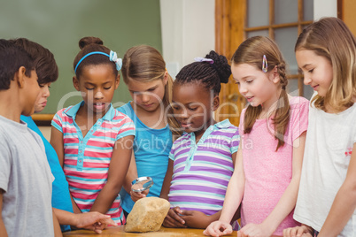 Pupils looking at rock with magnifying glass